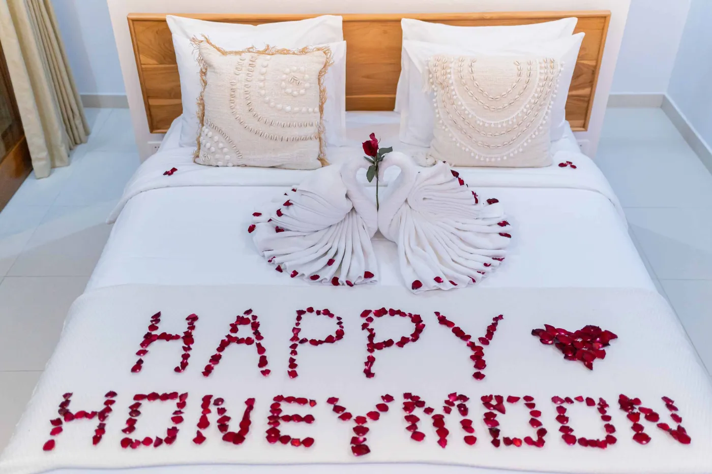 Bright modern Balinese kitchen with white countertops, wooden cabinets, potted plants, large windows, and a wall-mounted TV. - Bali Villas