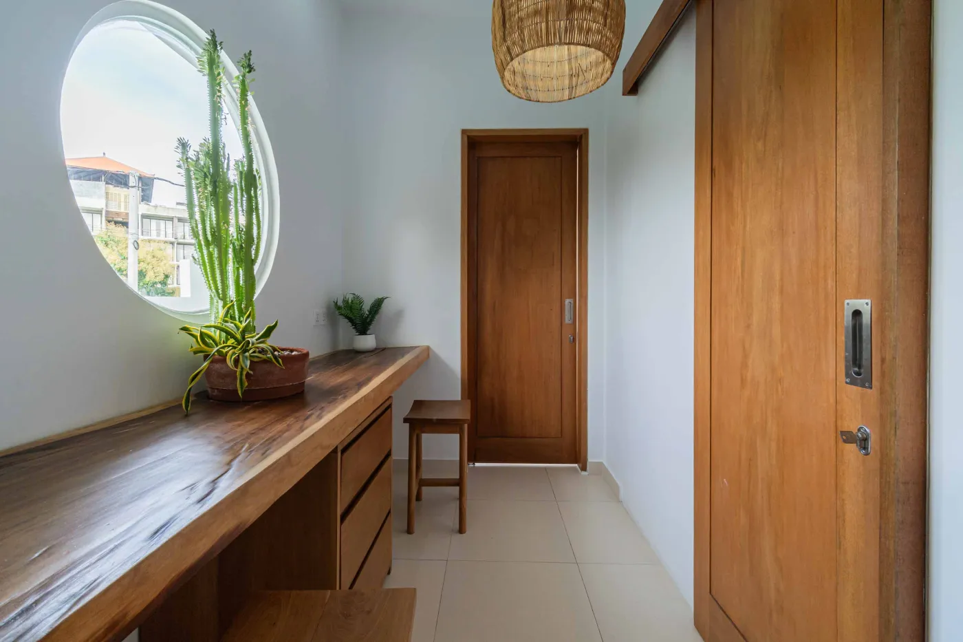 Bright modern Balinese kitchen with white countertops, wooden cabinets, potted plants, large windows, and a wall-mounted TV. - Bali Villas