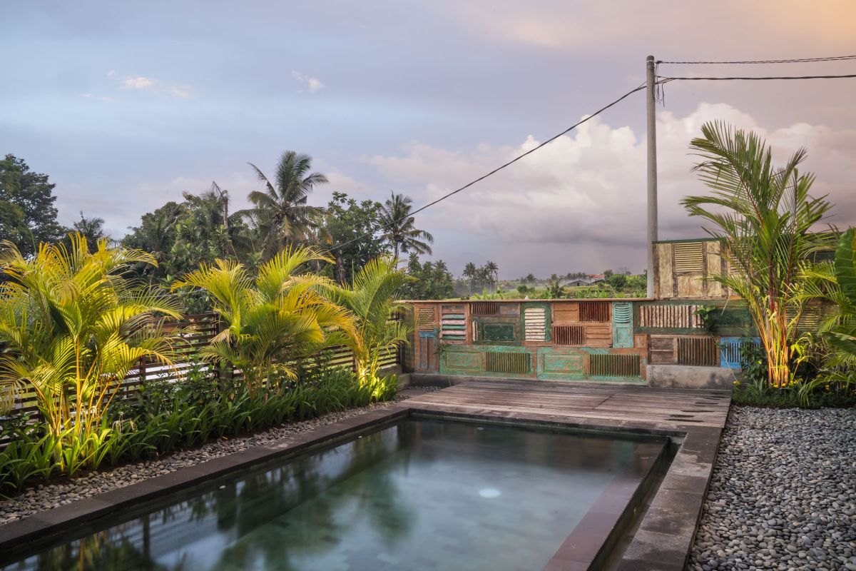 Rustic Balinese bathroom with wooden vanity, double sinks, orchid plant, towels, and pebble stone wall. - Bali Villas