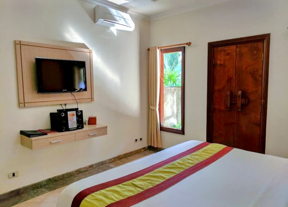Luxurious Balinese villa bedroom with king bed, red accents, and sliding doors to private infinity pool. - Bali Villas