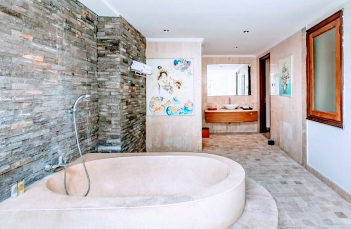 Luxurious Balinese villa bedroom with king bed, red accents, and sliding doors to private infinity pool. - Bali Villas