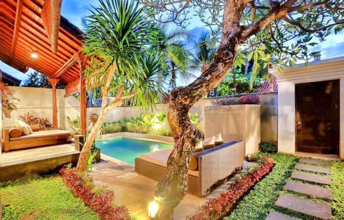 Luxurious Balinese villa bedroom with king bed, red accents, and sliding doors to private infinity pool. - Bali Villas