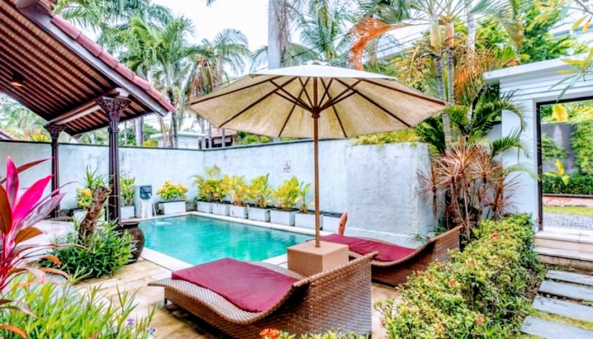 Luxurious Balinese villa bedroom with king bed, red accents, and sliding doors to private infinity pool. - Bali Villas