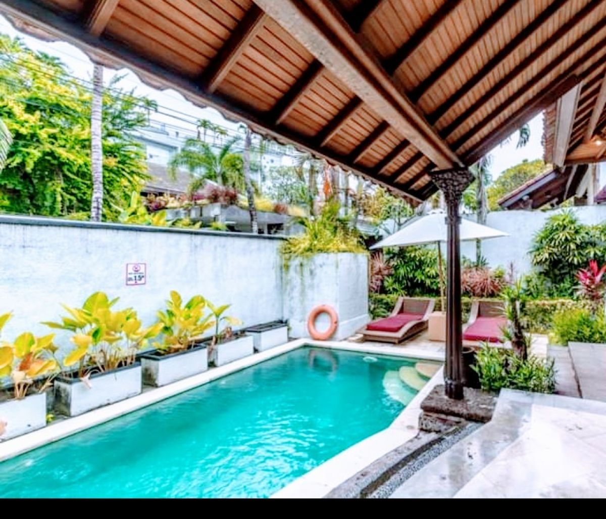 Luxurious Balinese villa bedroom with king bed, red accents, and sliding doors to private infinity pool. - Bali Villas