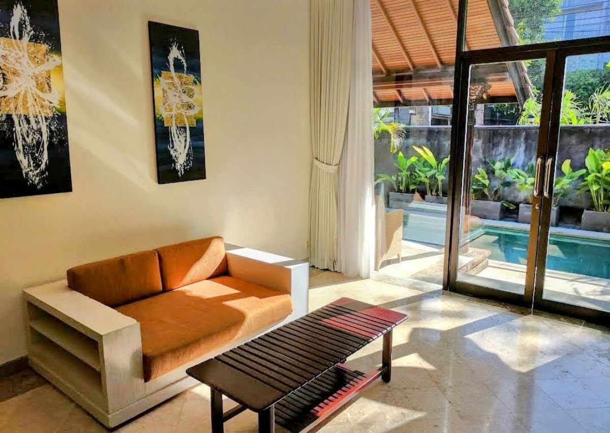 Luxurious Balinese villa bedroom with king bed, red accents, and sliding doors to private infinity pool. - Bali Villas