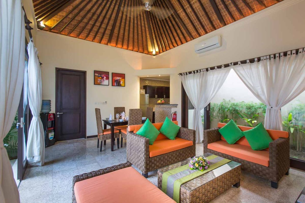 Modern U-shaped kitchen with dark wood cabinets, gold mosaic tile backsplash, granite counters, gas stove, and a bowl of fresh tropical fruits. - Bali Villas