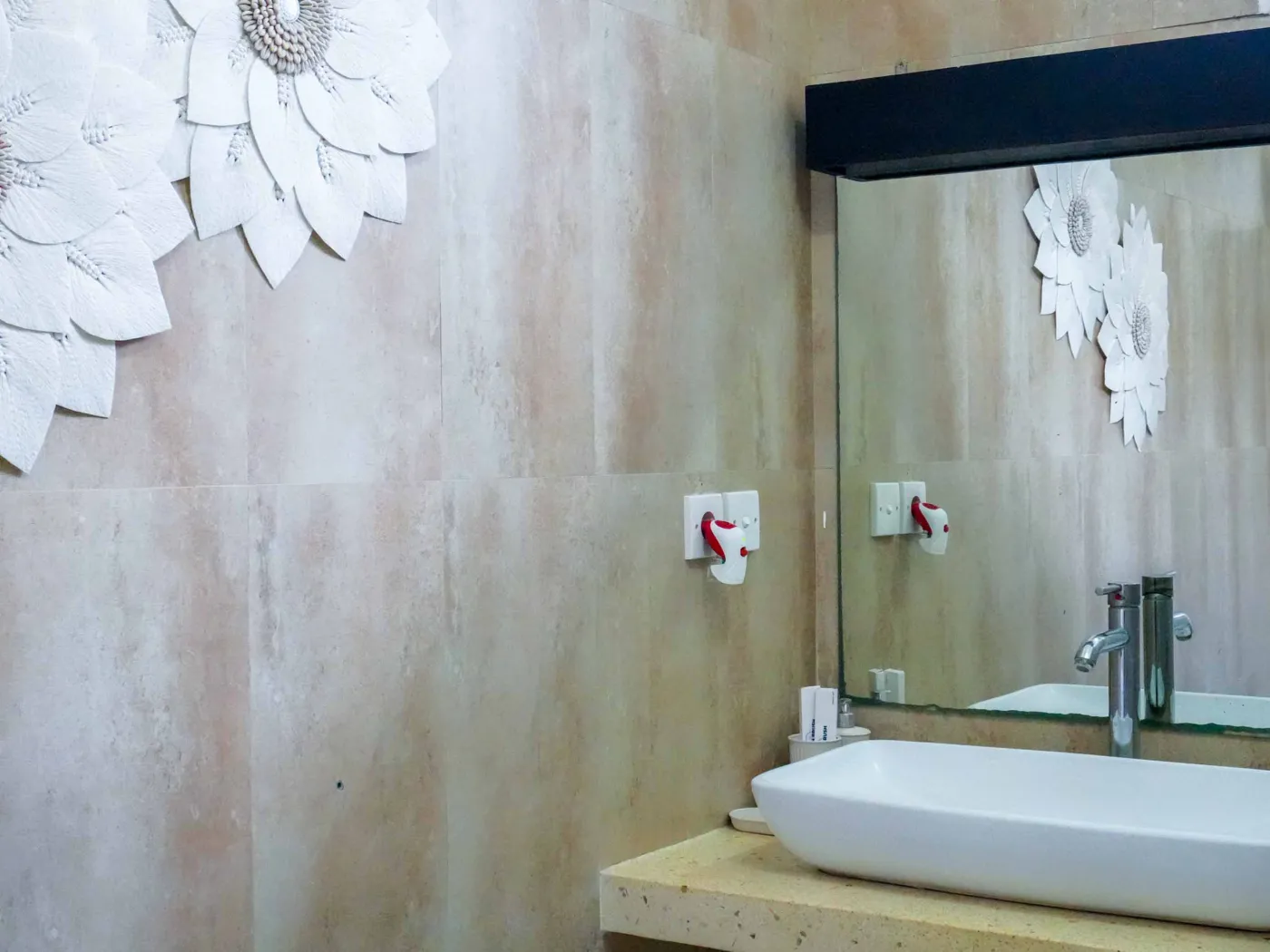 Modern compact kitchen featuring light wooden cabinets, black countertop, sink, microwave, toaster, and green mosaic backsplash. - Bali Villas