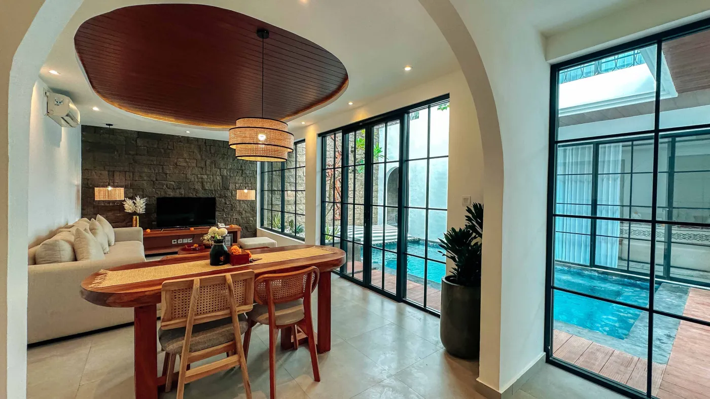 Elegant Balinese villa bedroom with king bed in flower petals spelling "HAPPY", arched wooden doors, bamboo accents, and white walls. - Bali Villas