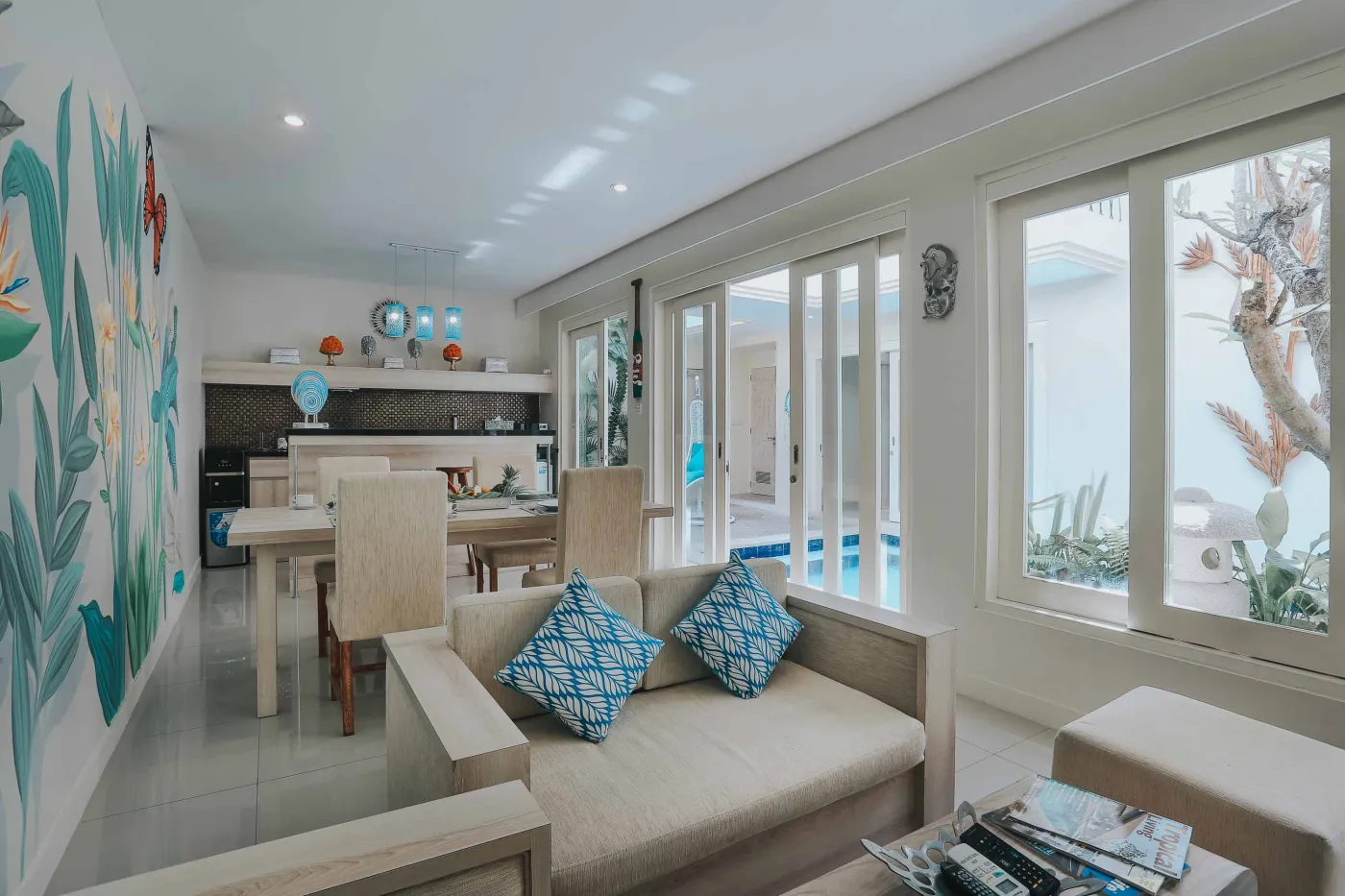Overhead view of a woman relaxing in a clawfoot bathtub filled with red rose petals, surrounded by tropical plants, Buddha statues, and spa amenities. - Bali Villas