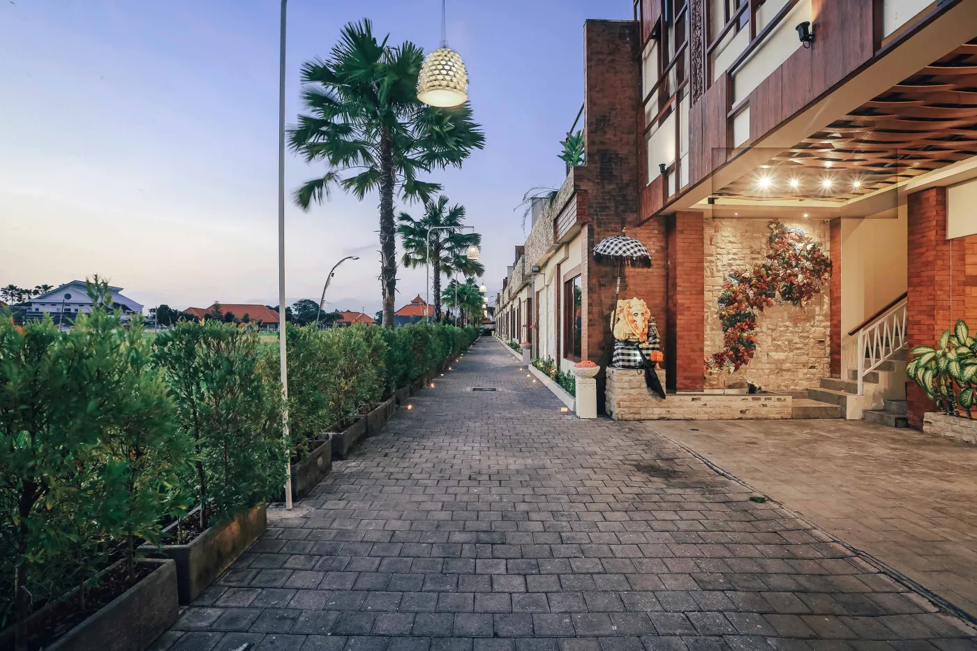 Luxurious Bali villa bedroom with king bed, wooden accents, wall mirror, and open balcony doors overlooking infinity pool and tropical palms. - Bali Villas