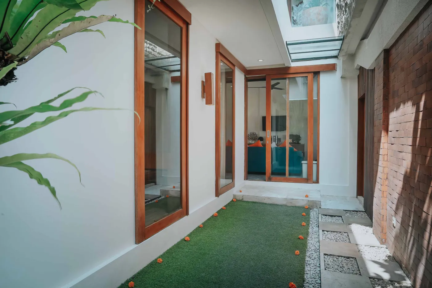 Modern luxury bathroom with freestanding white bathtub, glass shower enclosure, and floor-to-ceiling window overlooking tropical palm trees, pool, and villas. - Bali Villas