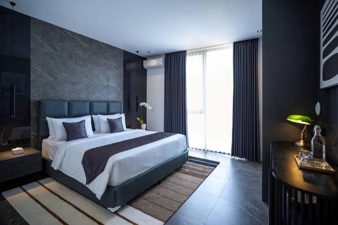 Modern minimalist bathroom with gray tiled walk-in shower, wooden slatted accents, wall-mounted toilet, and sleek vanity sink. - Bali Villas