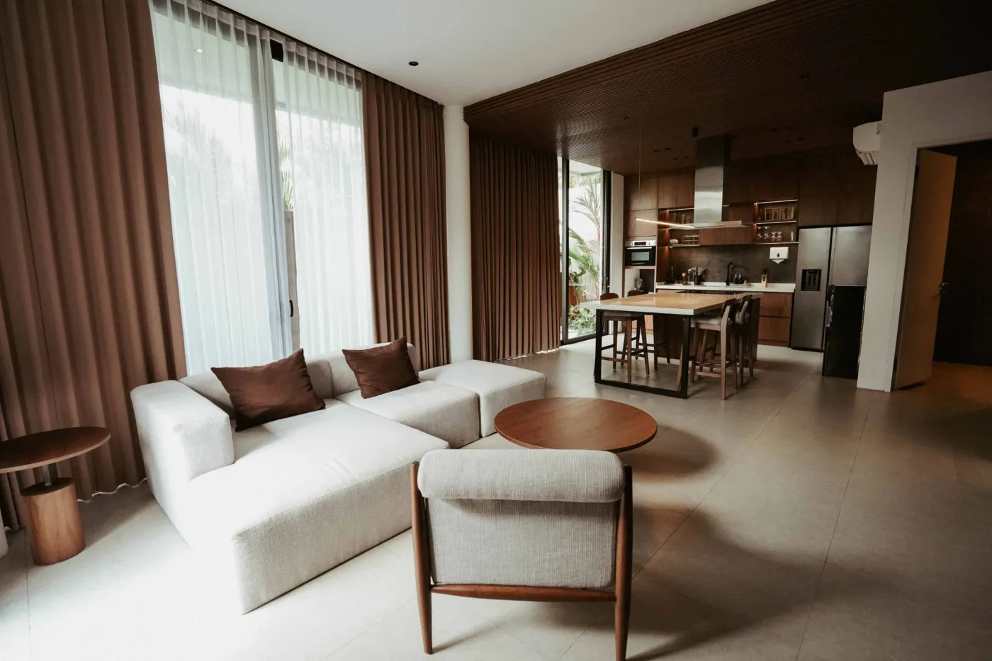 Modern minimalist bathroom with gray tiled walk-in shower, wooden slatted accents, wall-mounted toilet, and sleek vanity sink. - Bali Villas