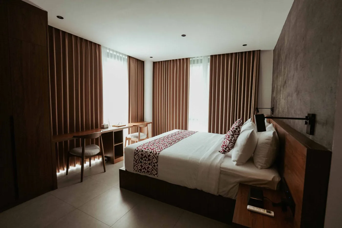 Modern minimalist bathroom with gray tiled walk-in shower, wooden slatted accents, wall-mounted toilet, and sleek vanity sink. - Bali Villas