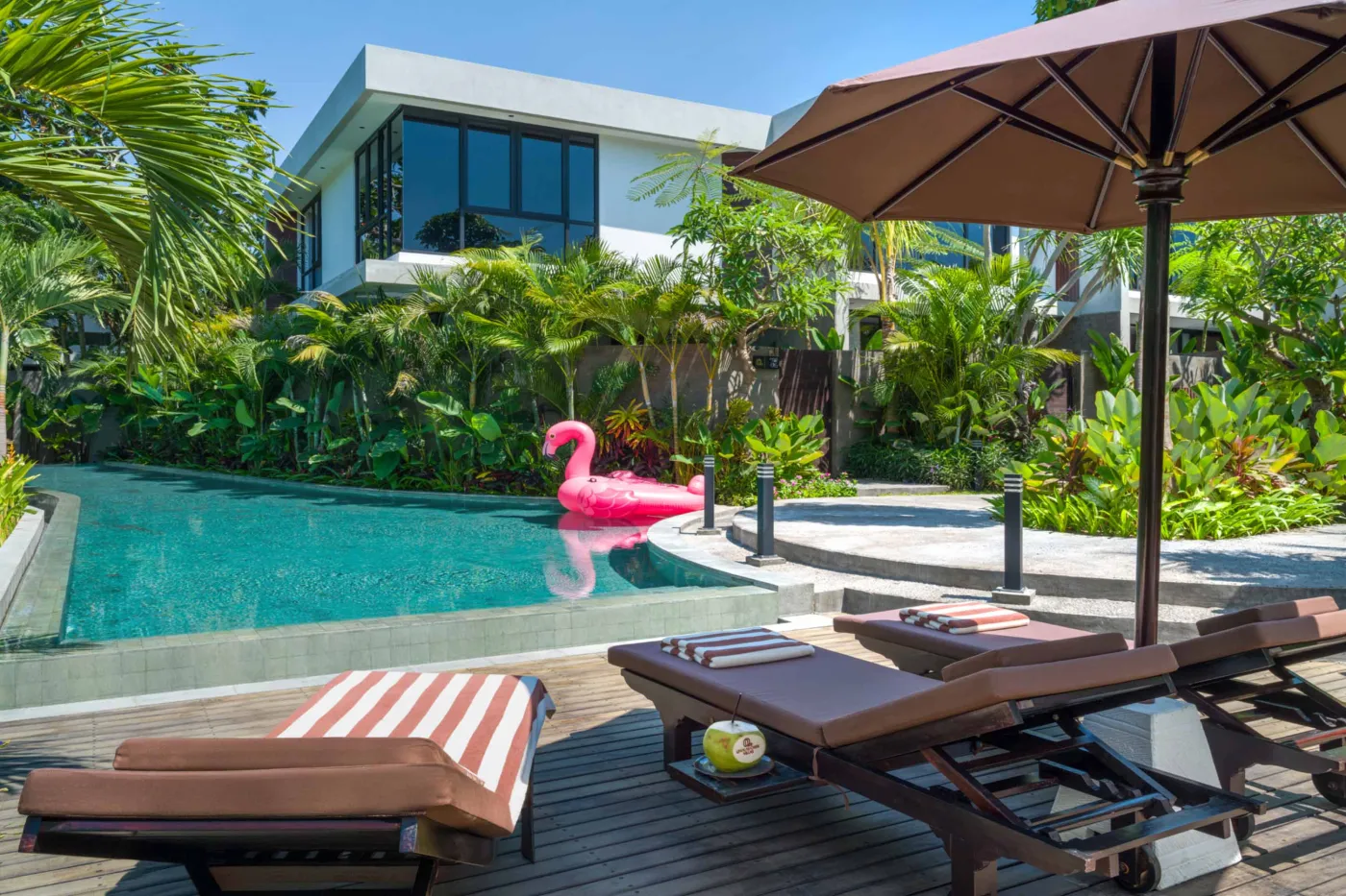 Serene private infinity pool in a tropical Bali villa, surrounded by lush palms, bean bag seating, and modern stone walls. - Bali Villas