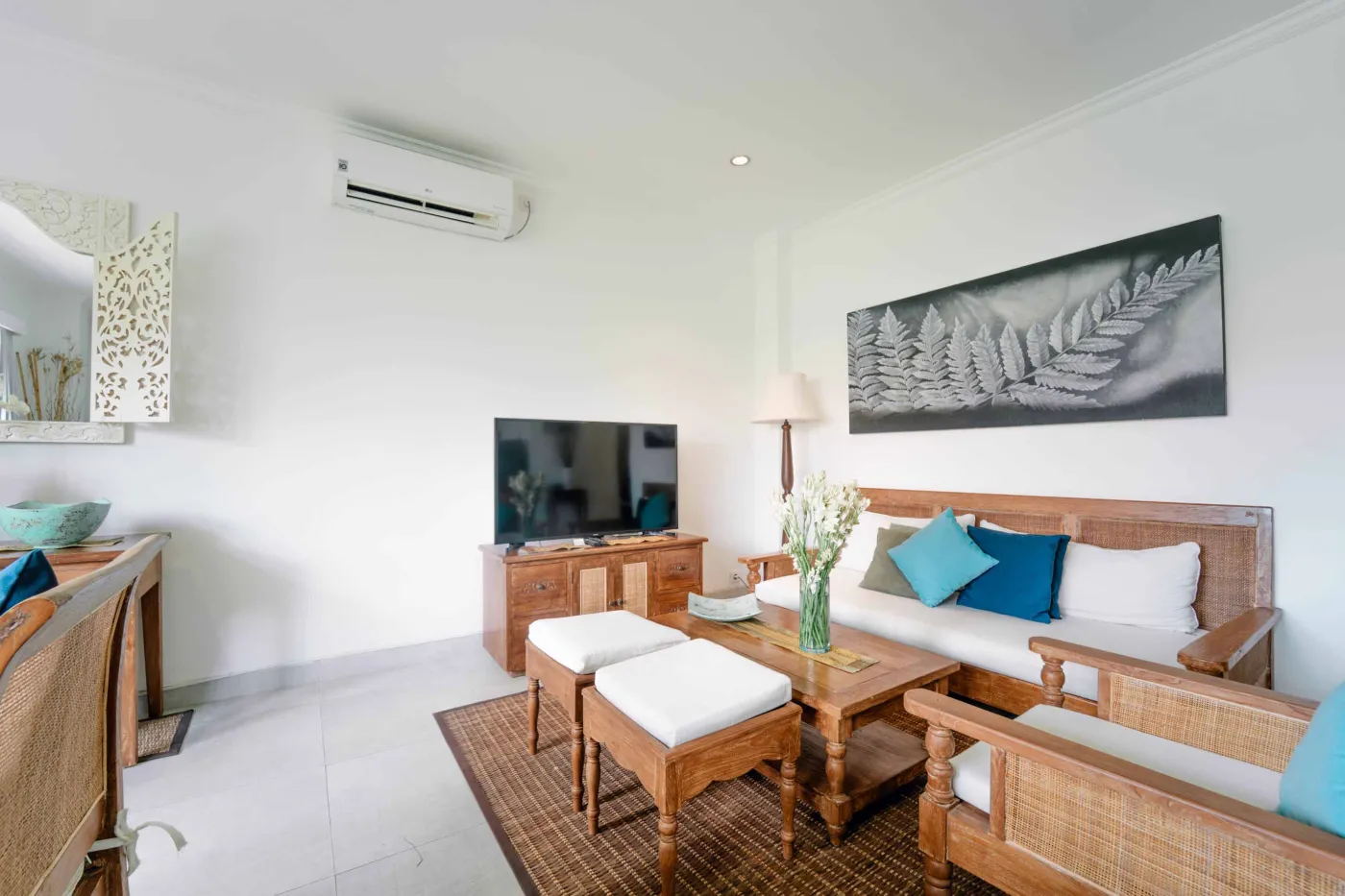 Modern bathroom featuring white toilet, glass shower enclosure, hanging towel, and wooden stool. - Bali Villas