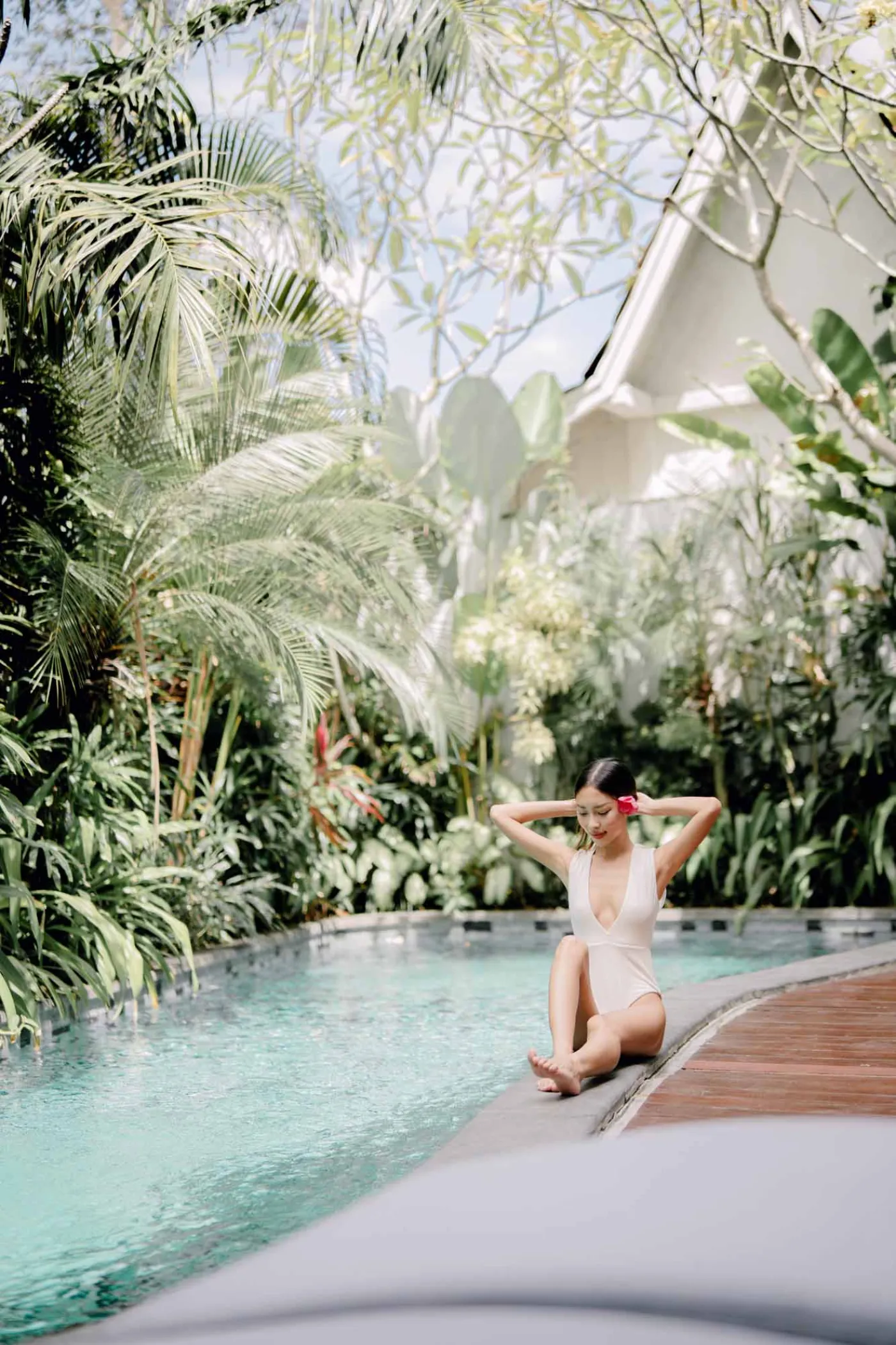 Modern white bathroom featuring a toilet, glass shower enclosure, hanging towel, and tiled walls. - Bali Villas