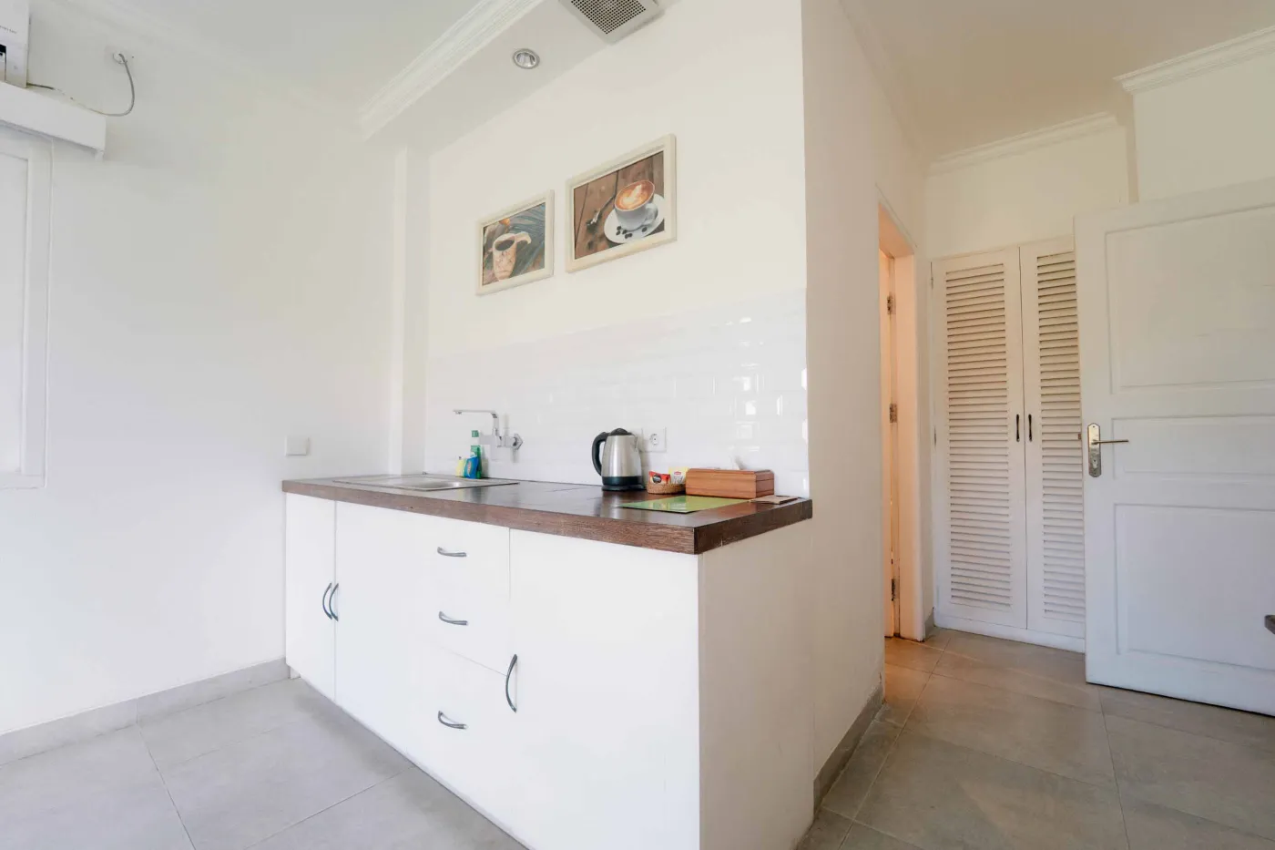 Modern white bathroom featuring a toilet, glass shower enclosure, hanging towel, and tiled walls. - Bali Villas