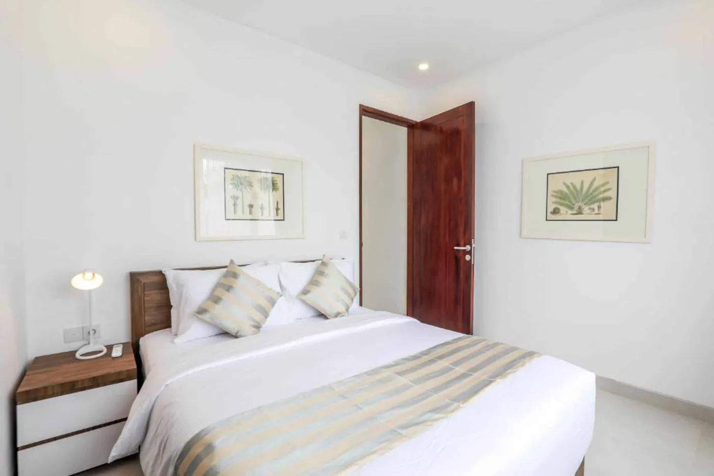 Modern Bali villa living room with beige sofas, glass dining table, Netflix on wall TV, potted plants, and sliding doors to infinity pool. - Bali Villas