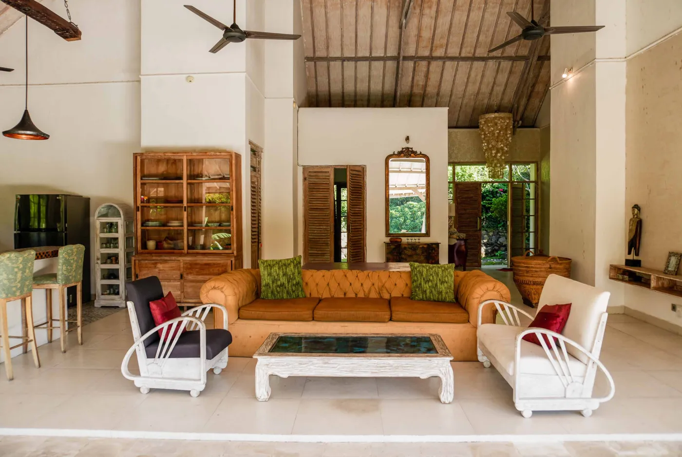 Spacious tropical villa interior with open wooden architecture, modern kitchen, cozy seating area, and lush garden view. - Bali Villas