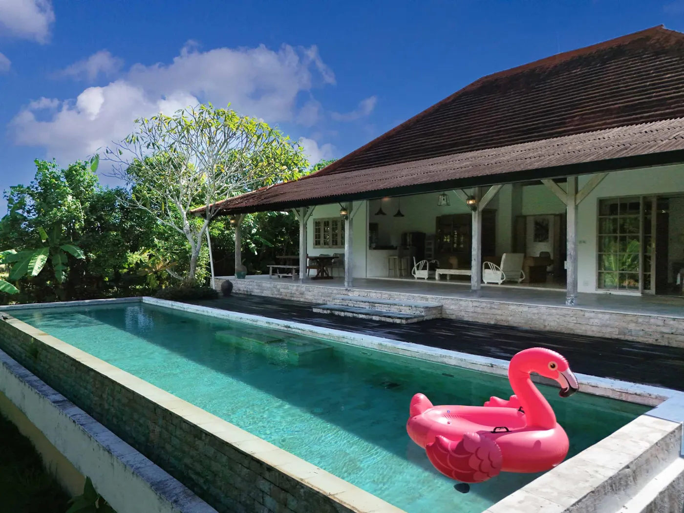 Spacious tropical villa interior with open wooden architecture, modern kitchen, cozy seating area, and lush garden view. - Bali Villas