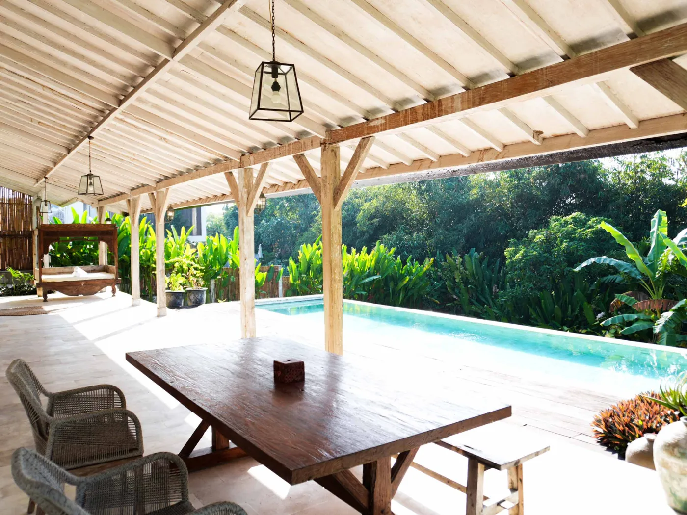 Spacious tropical villa interior with open wooden architecture, modern kitchen, cozy seating area, and lush garden view. - Bali Villas