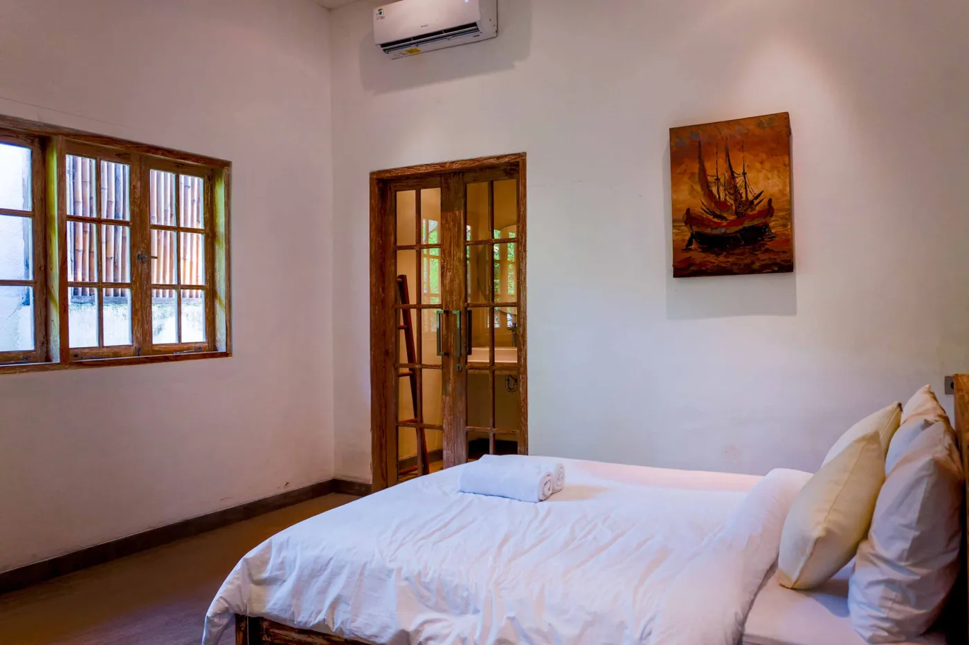 Spacious tropical villa interior with open wooden architecture, modern kitchen, cozy seating area, and lush garden view. - Bali Villas