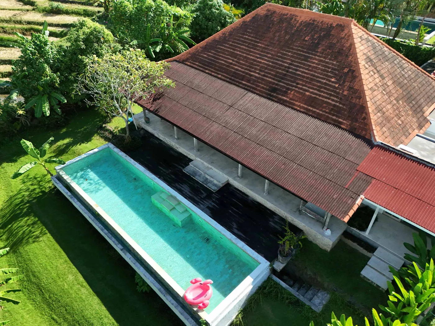 Spacious tropical villa interior with open wooden architecture, modern kitchen, cozy seating area, and lush garden view. - Bali Villas