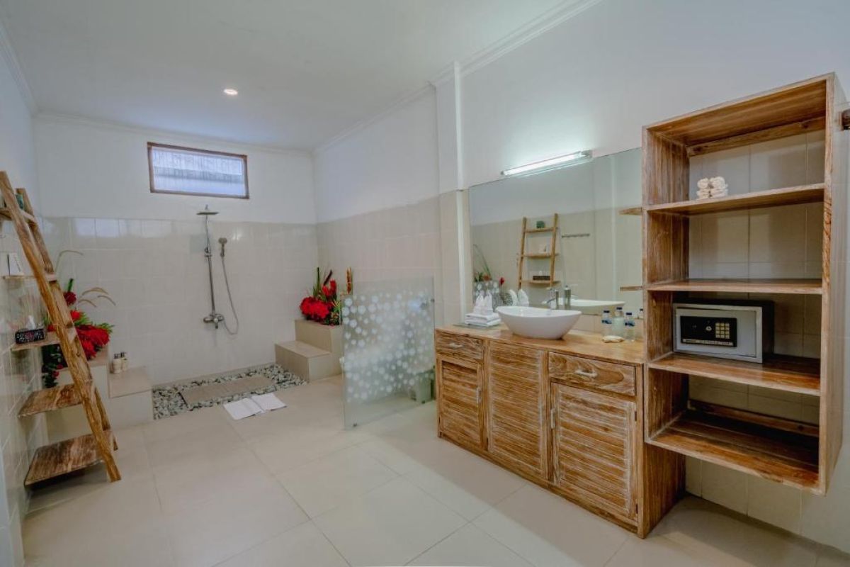 Modern white kitchen featuring wooden island, black granite counters, pull-out faucet sink, and woven pendant light. - Bali Villas