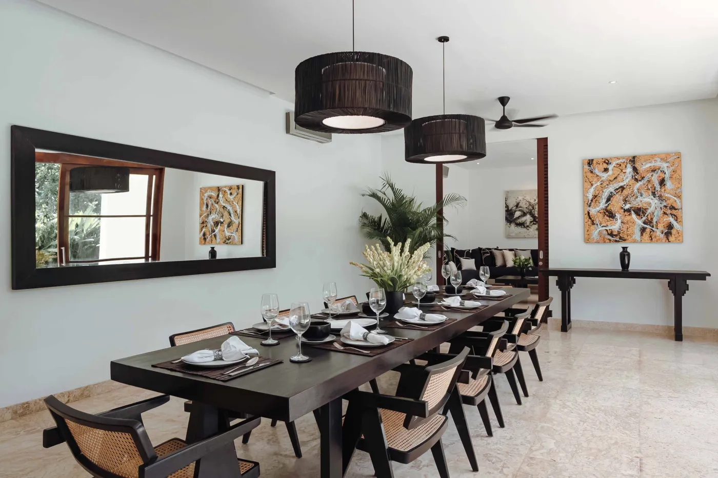 Modern tropical kitchen with white cabinets, granite island topped with fresh fruits, black appliances, and views of lush greenery. - Bali Villas