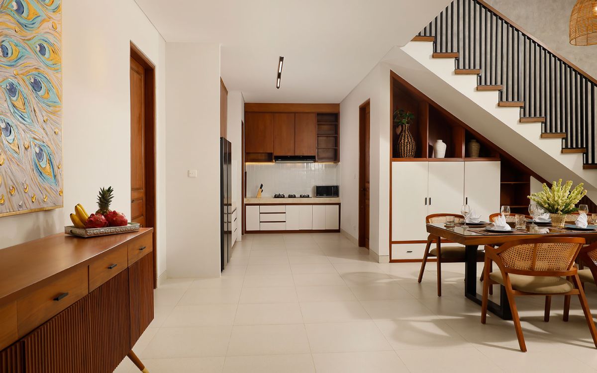 Spacious modern tropical bedroom with wooden bed, desk, mirror, and woven wall hangings under warm pendant lights. - Bali Villas