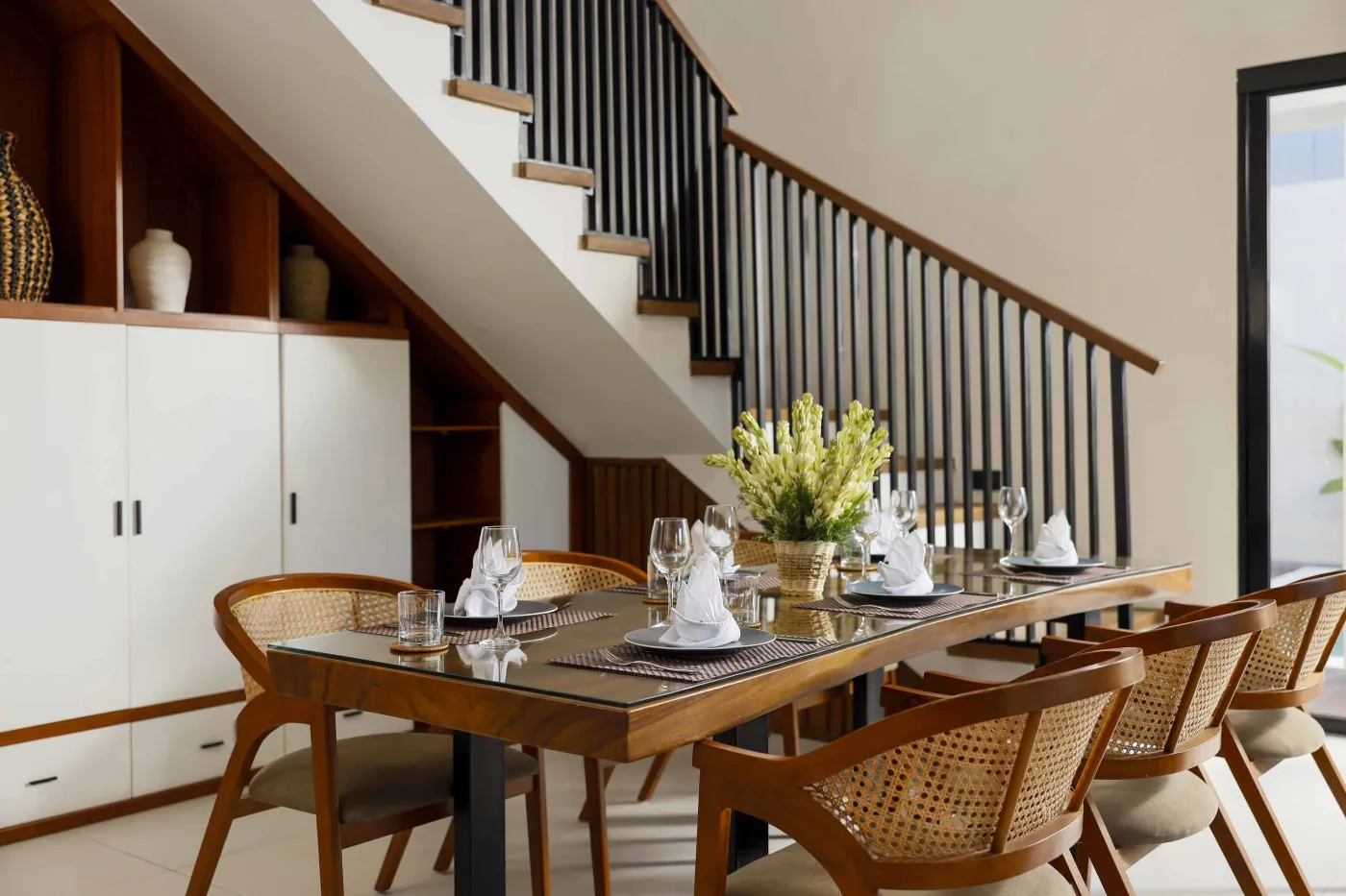 Modern open-plan kitchen and dining area with wooden furniture, tropical plants, and Balinese-style decor. - Bali Villas