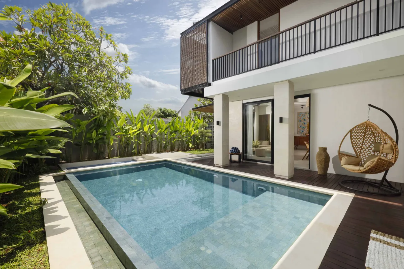 Modern open-plan kitchen and dining area with wooden furniture, tropical plants, and Balinese-style decor. - Bali Villas