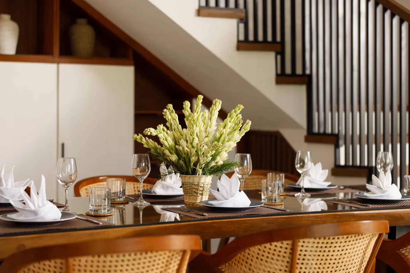 Modern open-plan kitchen and dining area with wooden furniture, tropical plants, and Balinese-style decor. - Bali Villas