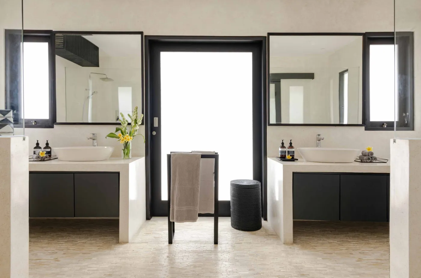 Well-stocked wooden wine cellar featuring diverse bottles of wine and spirits on shelves, with a small tasting table holding glasses and a red wine bottle. - Bali Villas