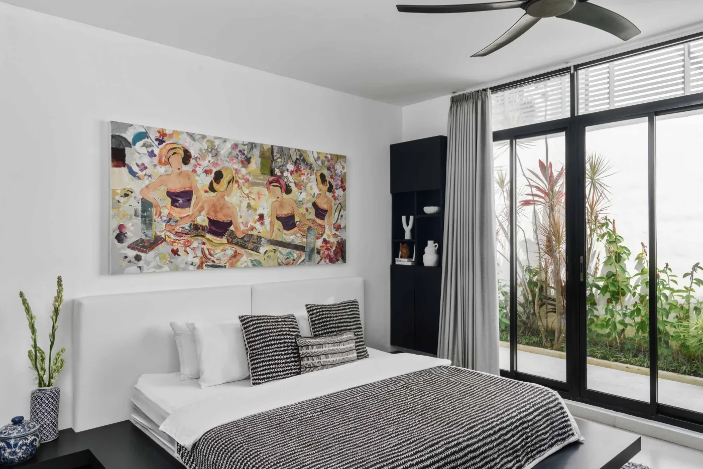 Well-stocked wooden wine cellar featuring diverse bottles of wine and spirits on shelves, with a small tasting table holding glasses and a red wine bottle. - Bali Villas