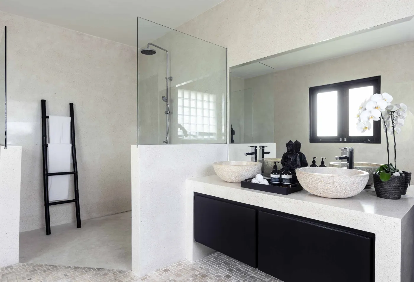 Well-stocked wooden wine cellar featuring diverse bottles of wine and spirits on shelves, with a small tasting table holding glasses and a red wine bottle. - Bali Villas