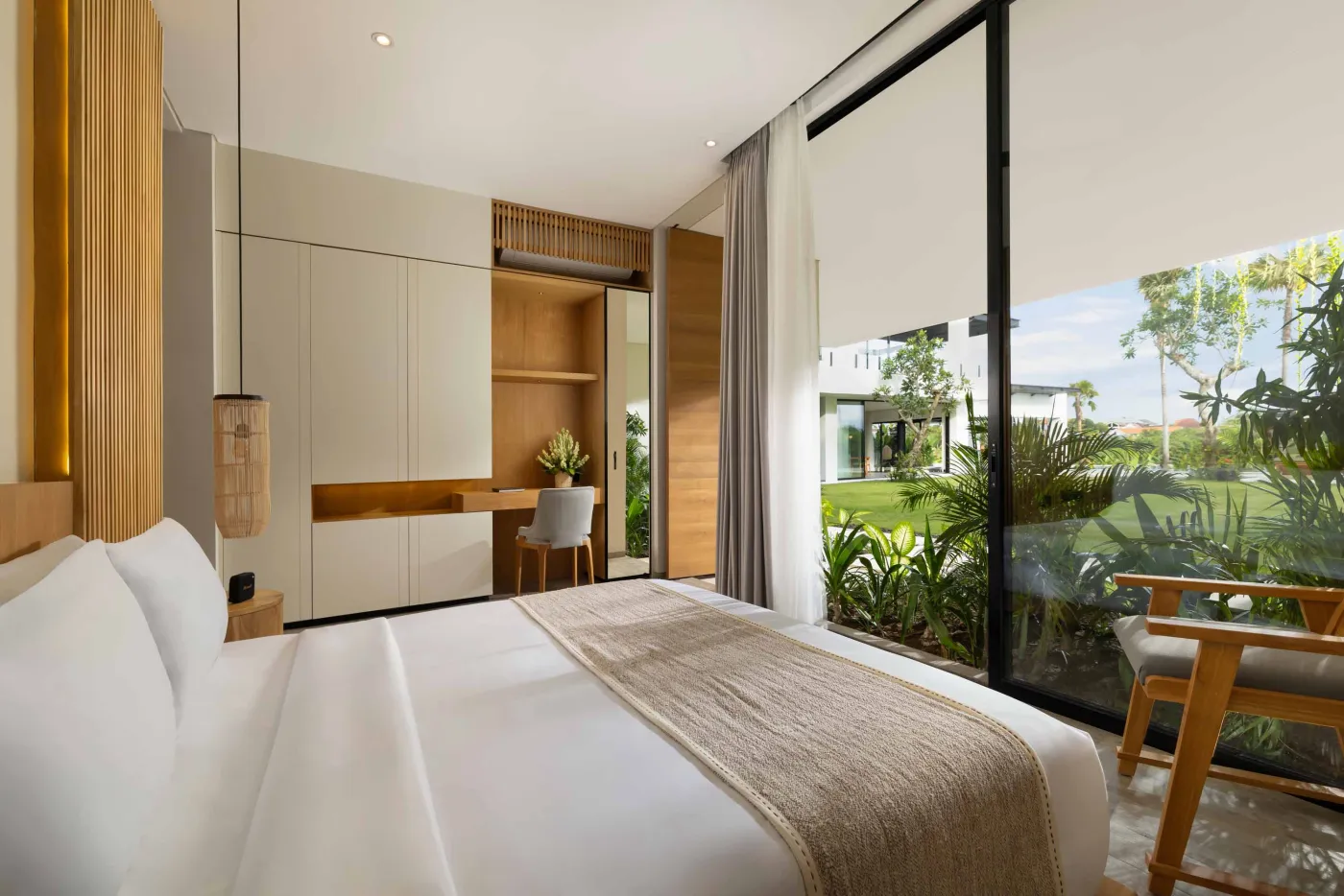Modern luxury bathroom with freestanding bathtub, walk-in rain shower, wooden accents, and bedroom view. - Bali Villas