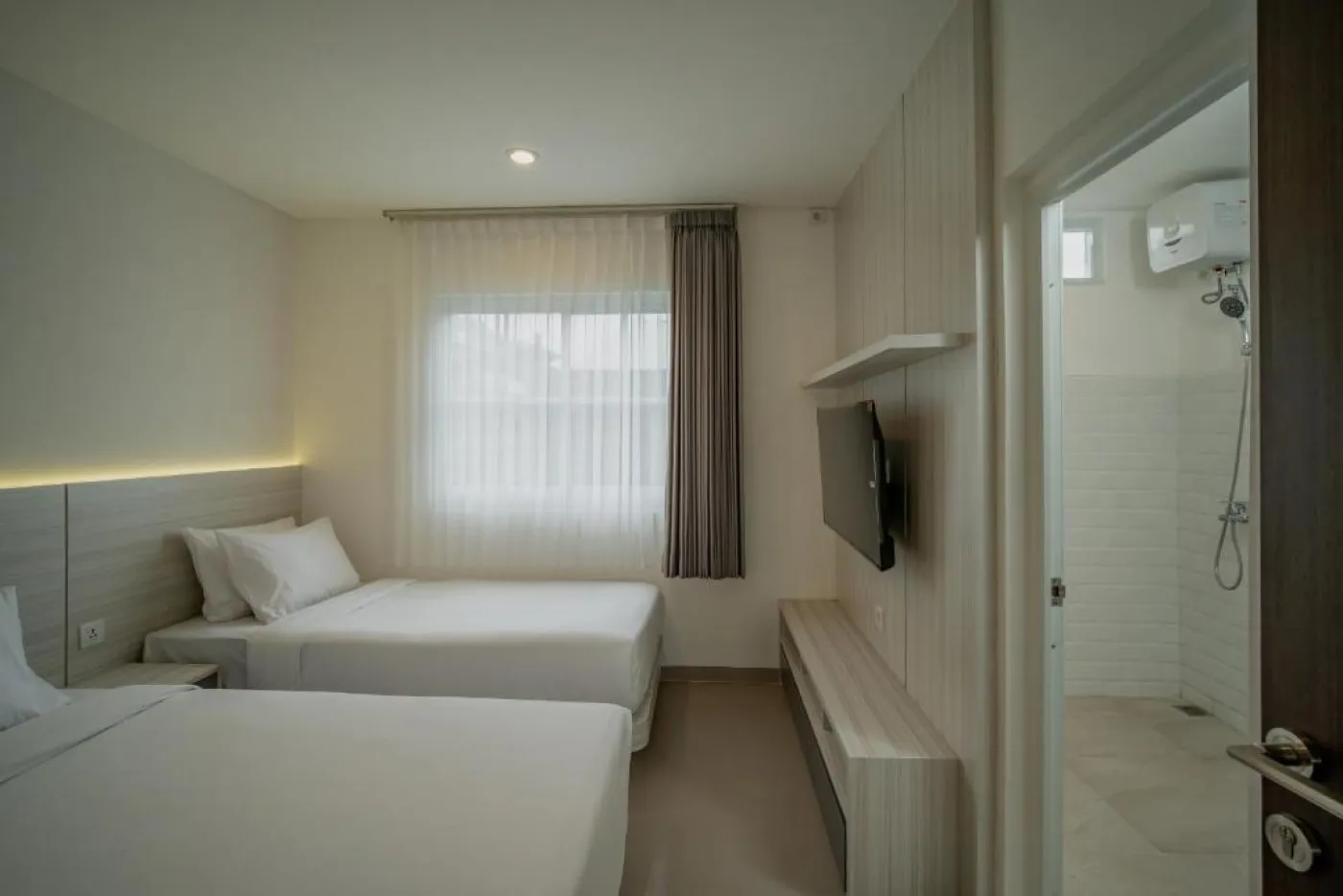 Modern white kitchen with sleek cabinets, induction cooktop, sink, microwave, and adjacent dining table with chairs. - Bali Villas