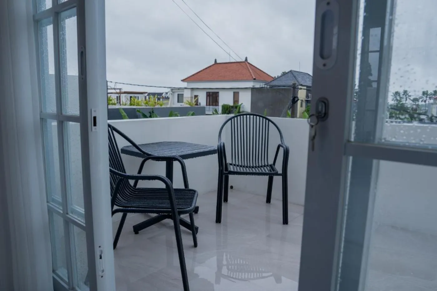 Modern white kitchen with sleek cabinets, induction cooktop, sink, microwave, and adjacent dining table with chairs. - Bali Villas