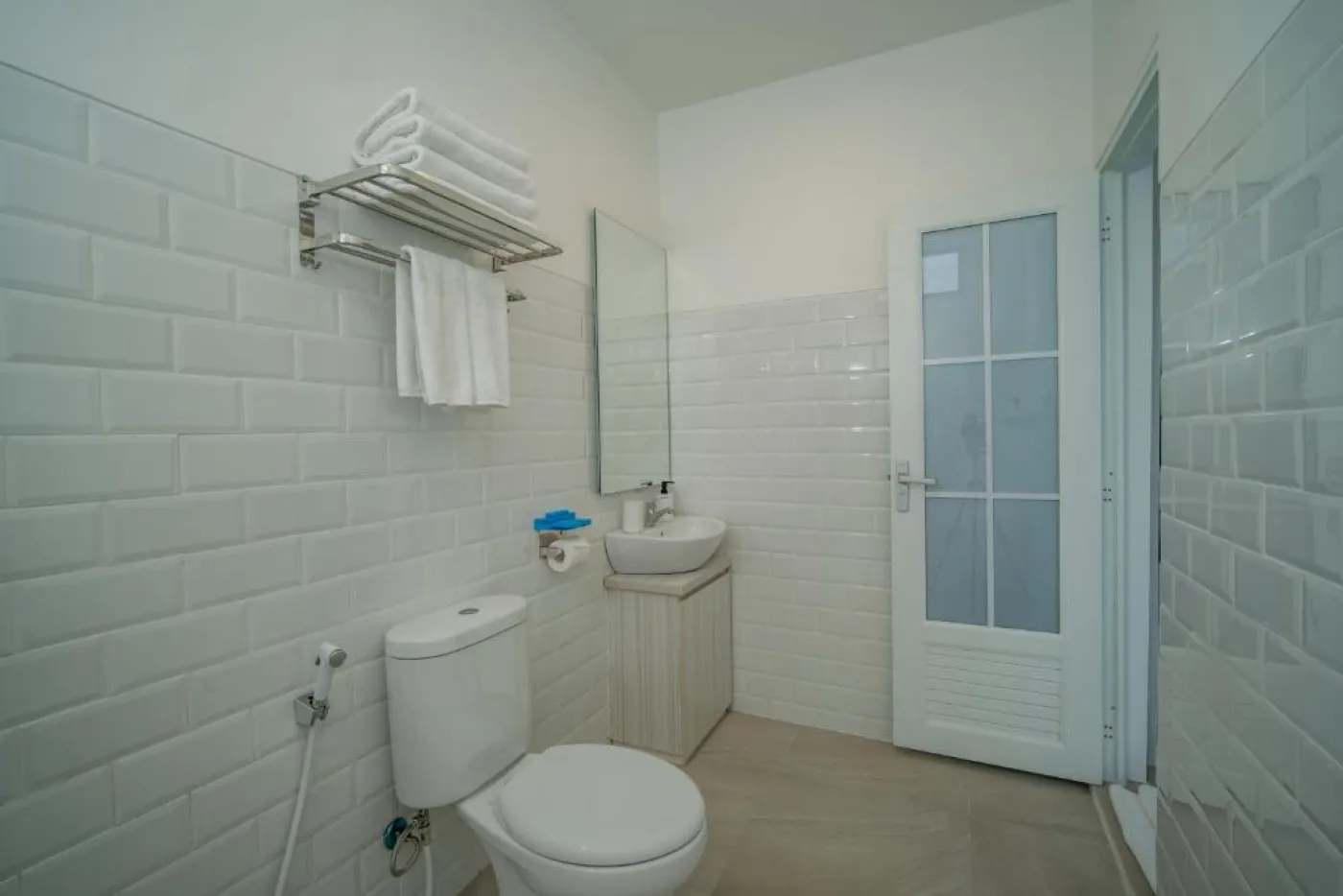 Modern minimalist living room interior with gray sofa, wooden coffee table, wall-mounted TV, built-in white shelves, and adjacent stairs. - Bali Villas