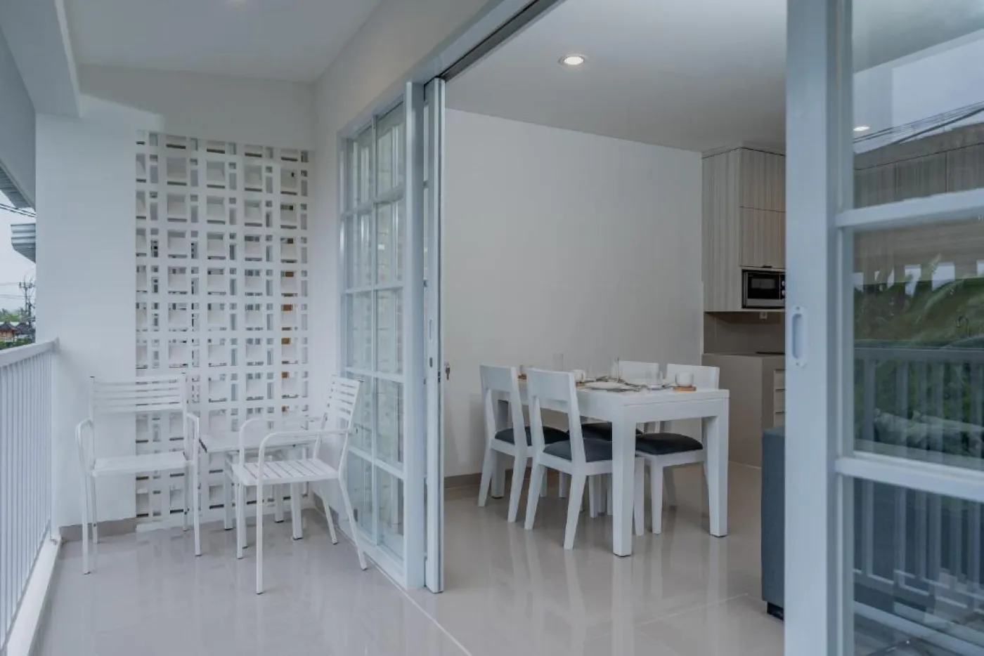 Modern minimalist living room interior with gray sofa, wooden coffee table, wall-mounted TV, built-in white shelves, and adjacent stairs. - Bali Villas