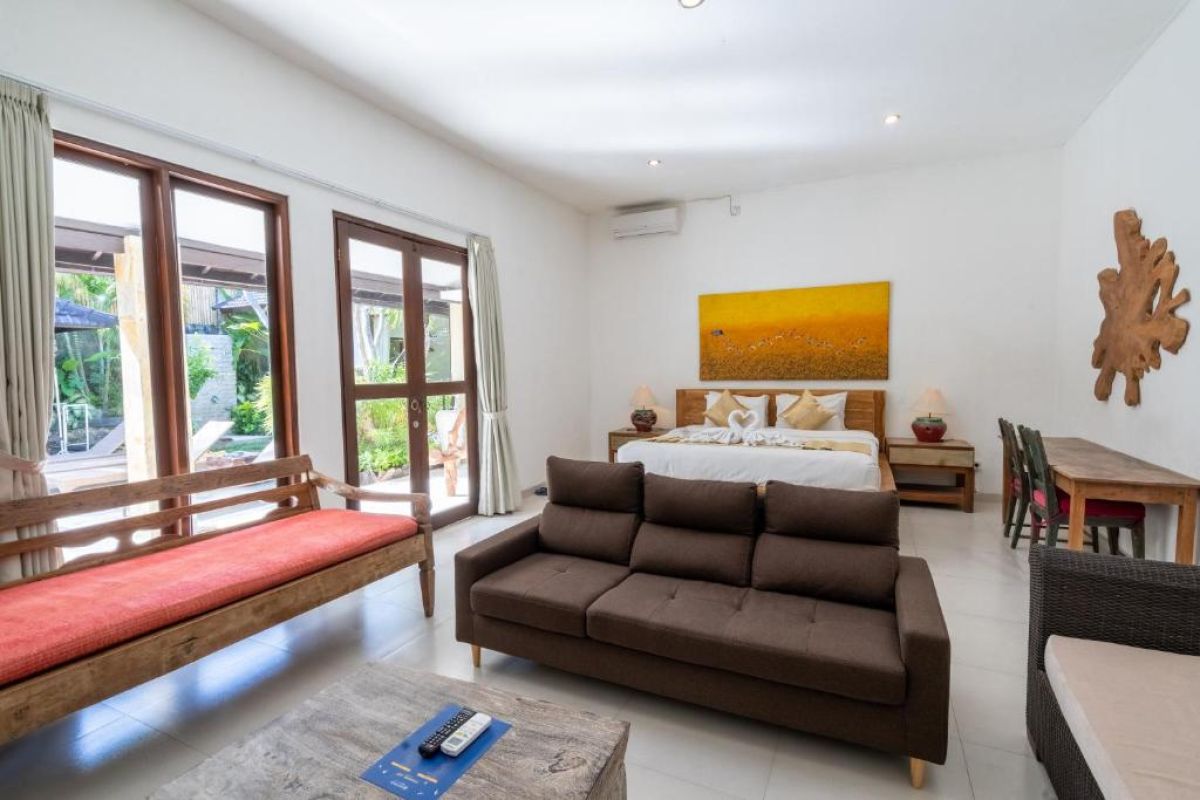 Spacious Balinese-style kitchen with intricate tiled walls, wooden cabinets, central island counter, and stainless steel appliances. - Bali Villas