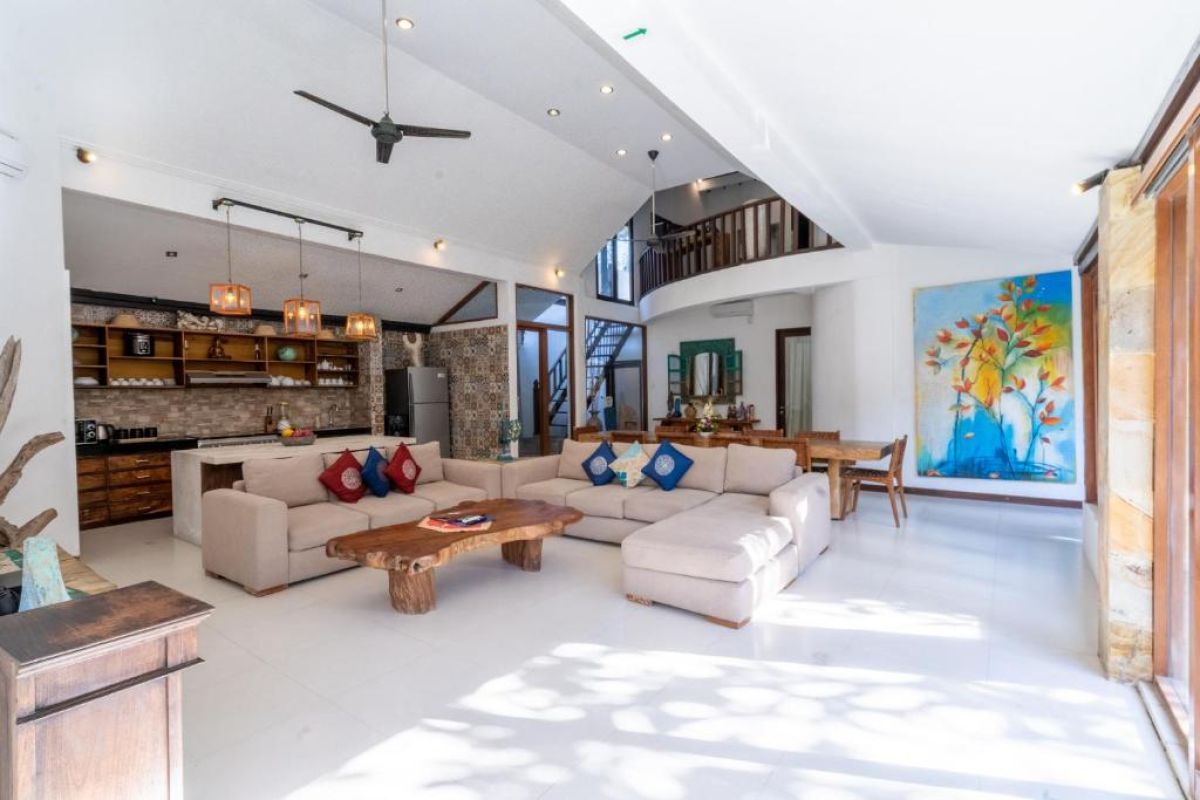 Spacious Balinese-style kitchen with intricate tiled walls, wooden cabinets, central island counter, and stainless steel appliances. - Bali Villas