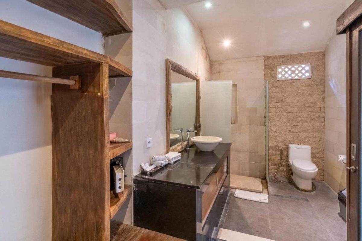 Spacious Balinese-style kitchen with intricate tiled walls, wooden cabinets, central island counter, and stainless steel appliances. - Bali Villas