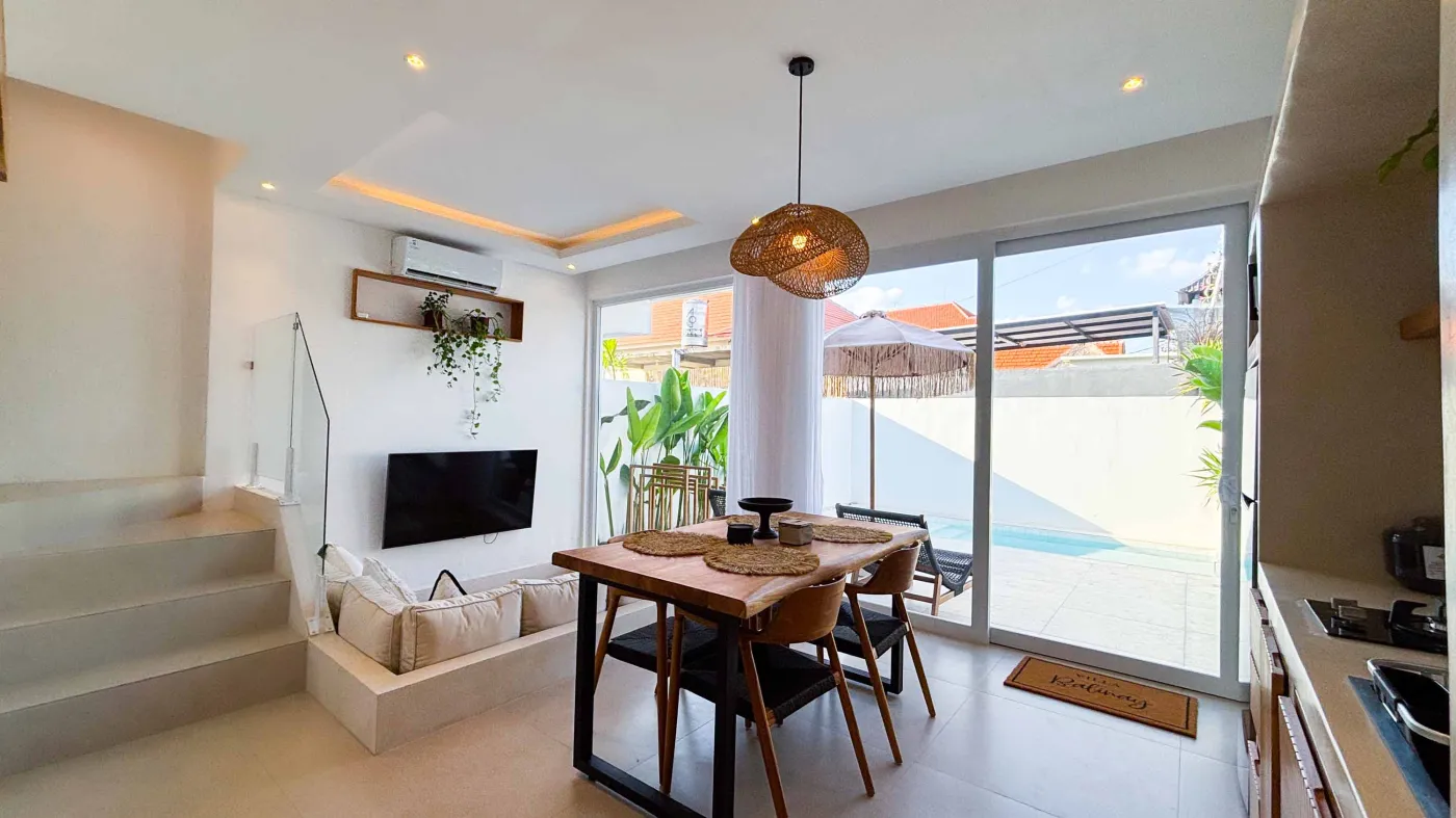 Modern minimalist bathroom with white stone sink, black fixtures, glass shower enclosure, and folded towels on counter. - Bali Villas