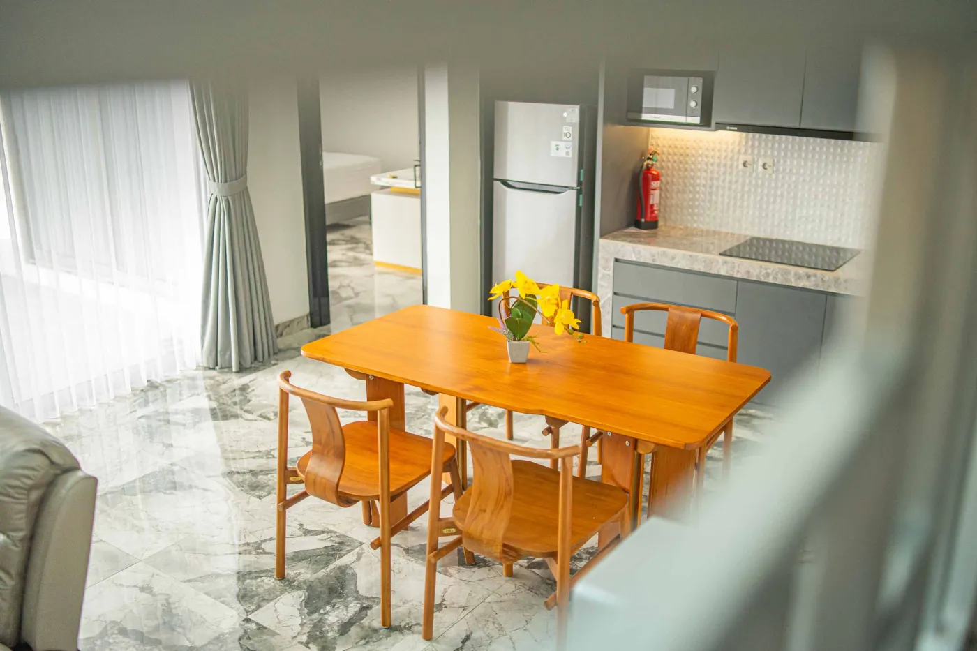 Modern living room interior with beige L-shaped sofa, wall-mounted TV, blue LED ceiling lights, textured gray wall, and potted plants. - Bali Villas