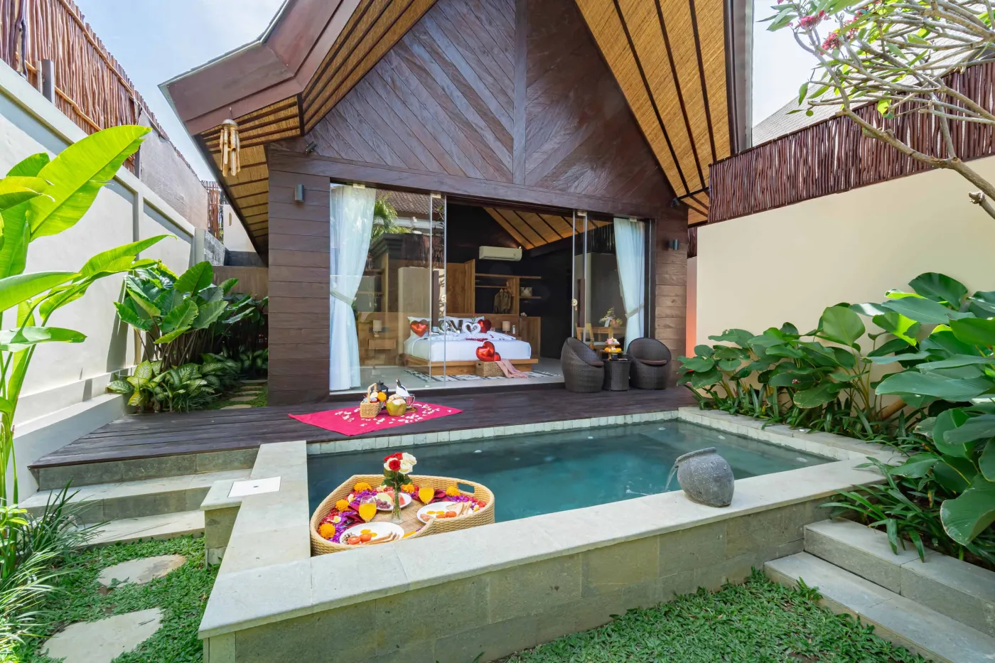 Luxurious Balinese villa bedroom with private plunge pool, floating frangipani flowers, and tropical garden surroundings. - Bali Villas