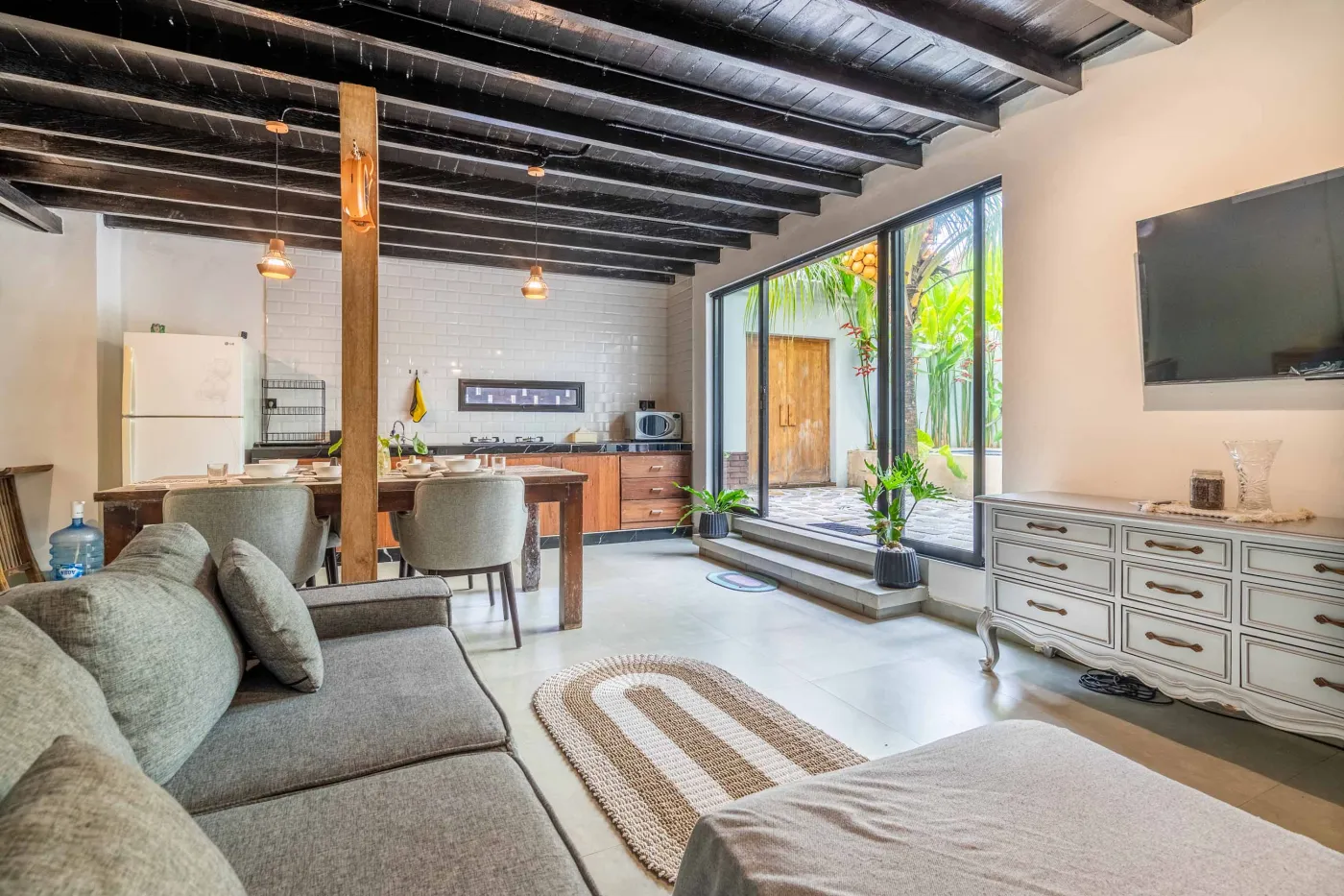 Modern white-tiled bathroom with glass shower enclosure, sink, and toilet. - Bali Villas