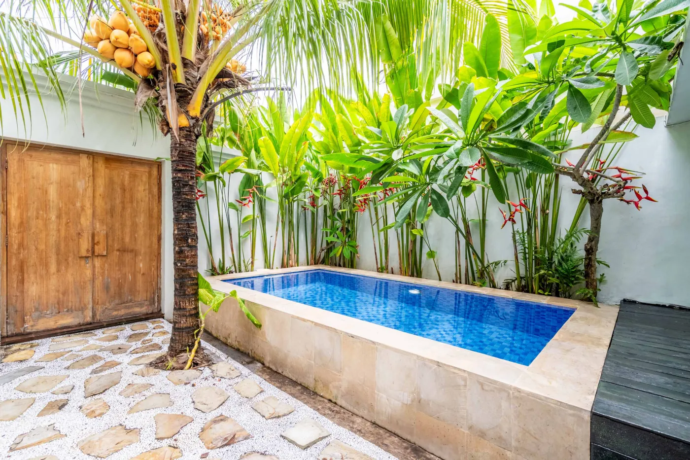 Modern white-tiled bathroom with glass shower enclosure, sink, and toilet. - Bali Villas